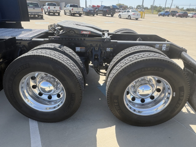 Peterbilt 579 truck chassis showing dual rear axles with polished chrome rims and tires, part of the fifth wheel and frame visible.