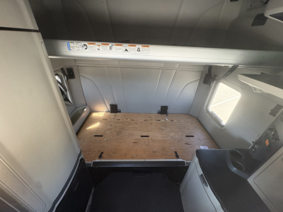 Peterbilt 579 sleeper cab cargo area interior showing wooden floor panel and side wall panels.