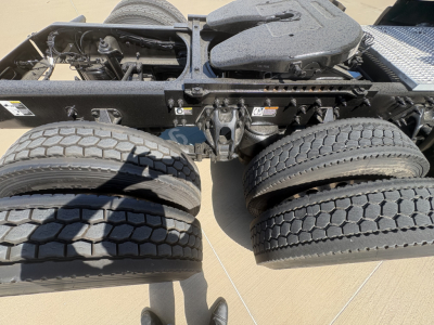 Truck chassis and dual rear axles with tires; frame rails, mounting hardware, and a fifth-wheel hitch visible.