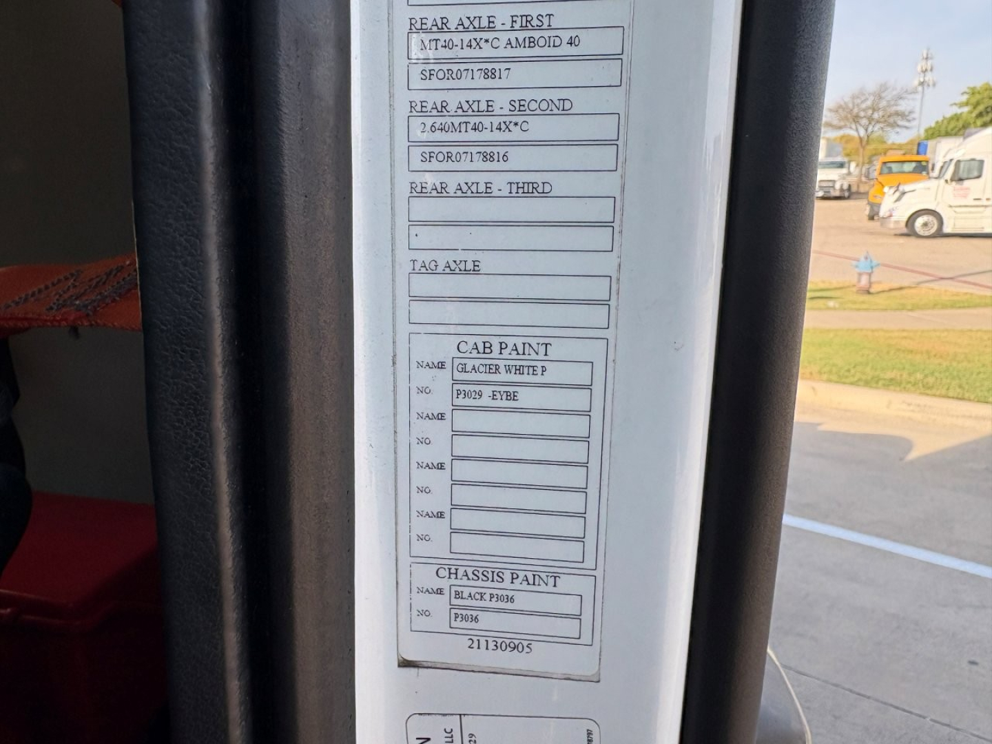 Label sticker on the cab door showing axle specifications, cab paint, and chassis paint details. Text fragments visible include REAR AXLE - FIRST, REAR AXLE - SECOND, REAR AXLE - THIRD, CAB PAINT, CHASSIS PAINT, and numbers/NAP codes.