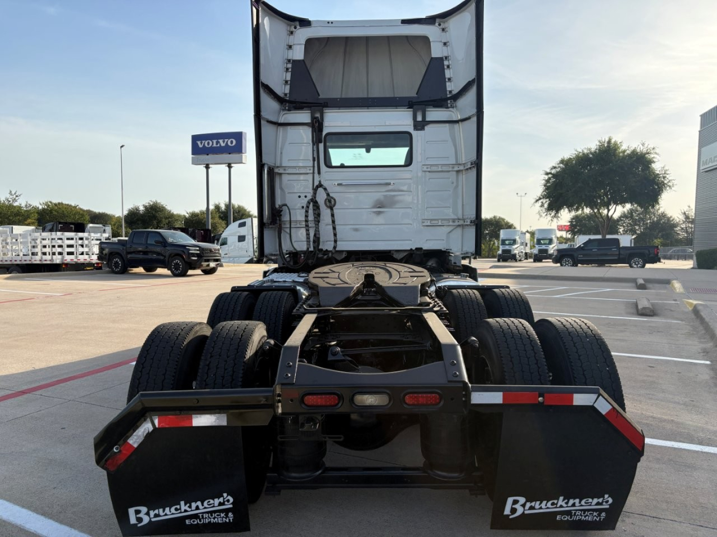 Truck chassis rear view showing fifth wheel, dual rear axles, and mud flaps with Bruckner's branding. Cab is white with exposed frame and rear window.