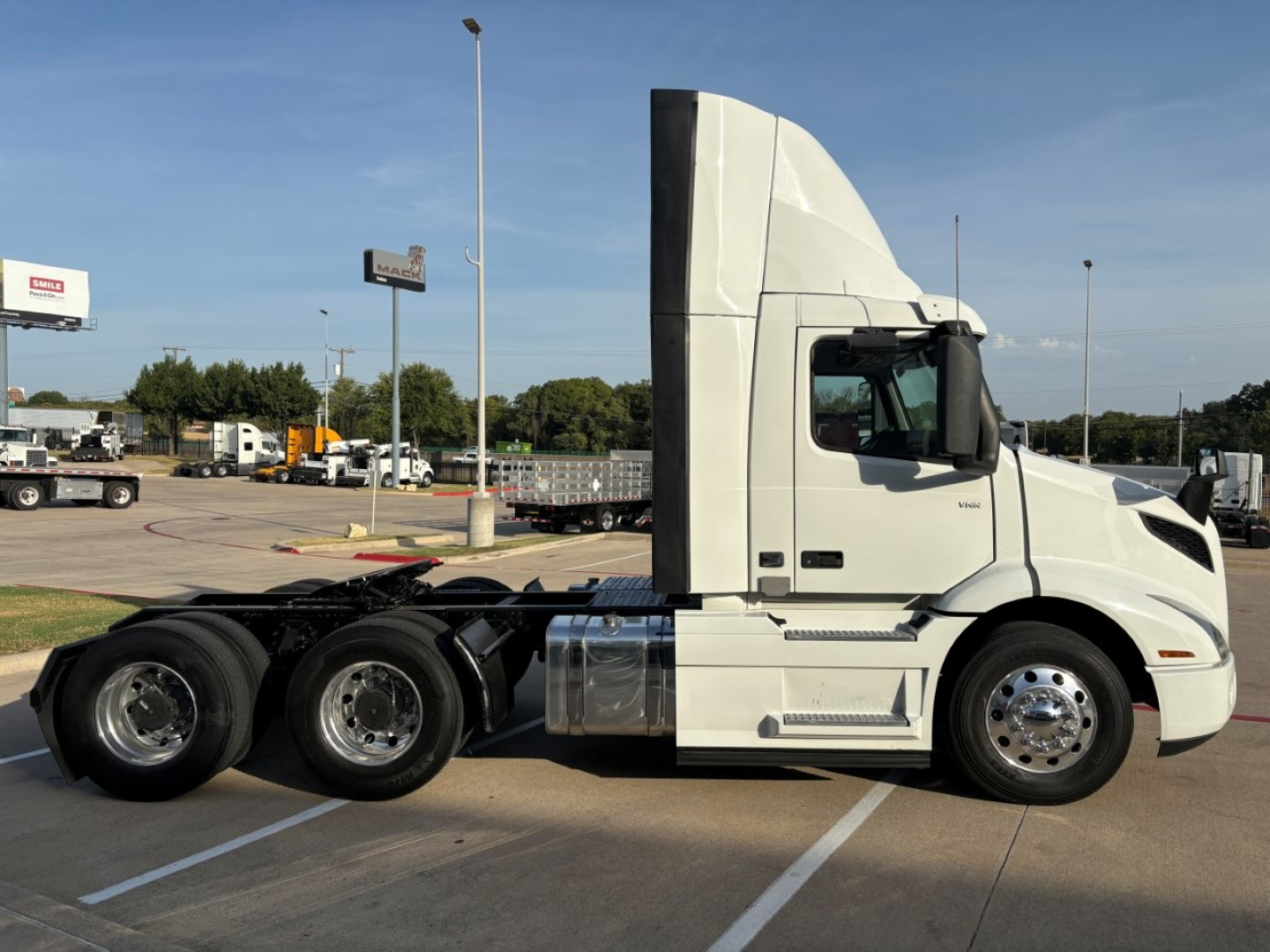 Volvo VNR64T300 tractor cab side view showing tandem rear axles and chrome fuel tanks.