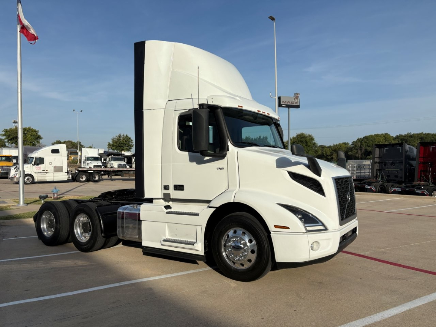 Volvo VNR64T300 tractor in a parking lot, side view showing cab and front wheels.