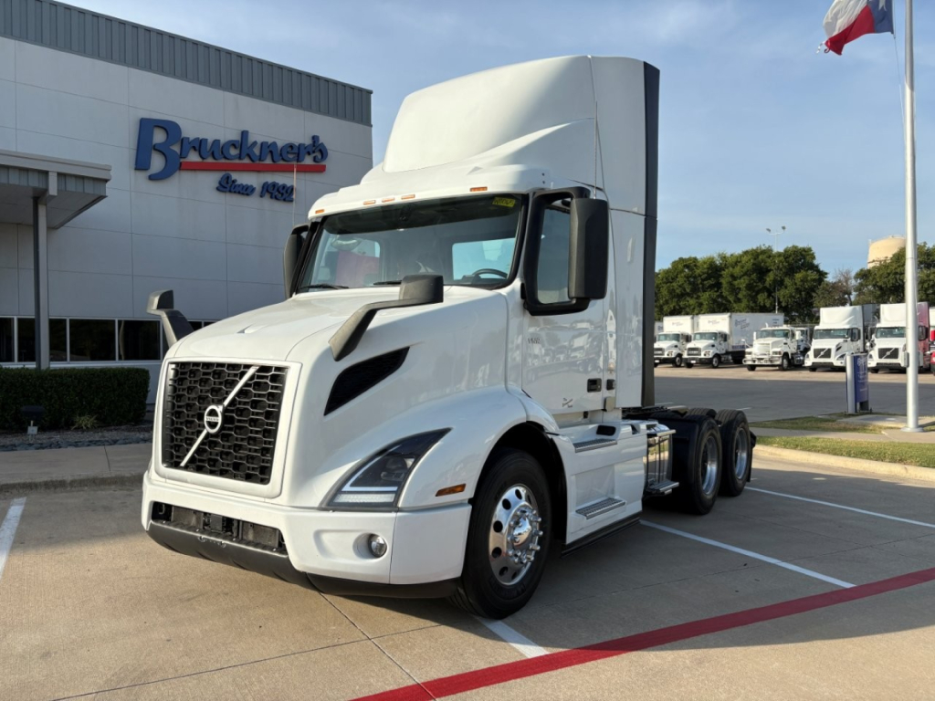 Volvo VNR64T300 semi-truck tractor in white parked outside dealership showing aerodynamic cab and dual rear axles.