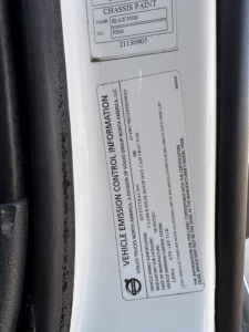 Vehicle emission control information label on Volvo VNR64T300 cab door frame showing text and numbers.