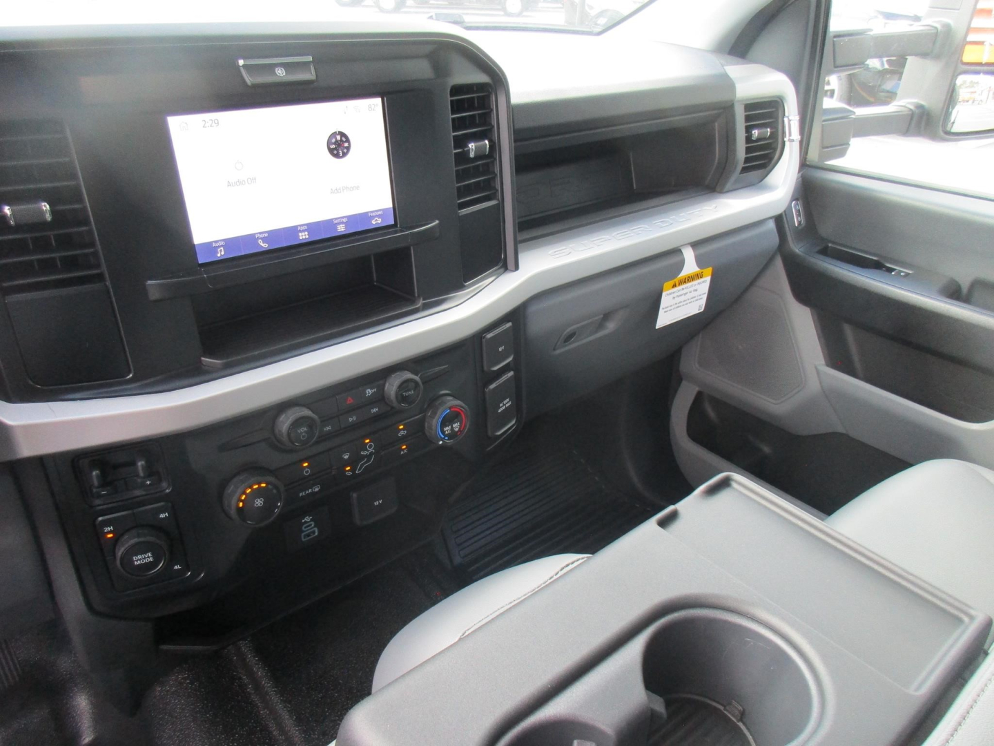 Ford F-450 cabin interior with center touchscreen display, dashboard controls, ash-gray seats; front passenger area visible in a new flatbed truck.