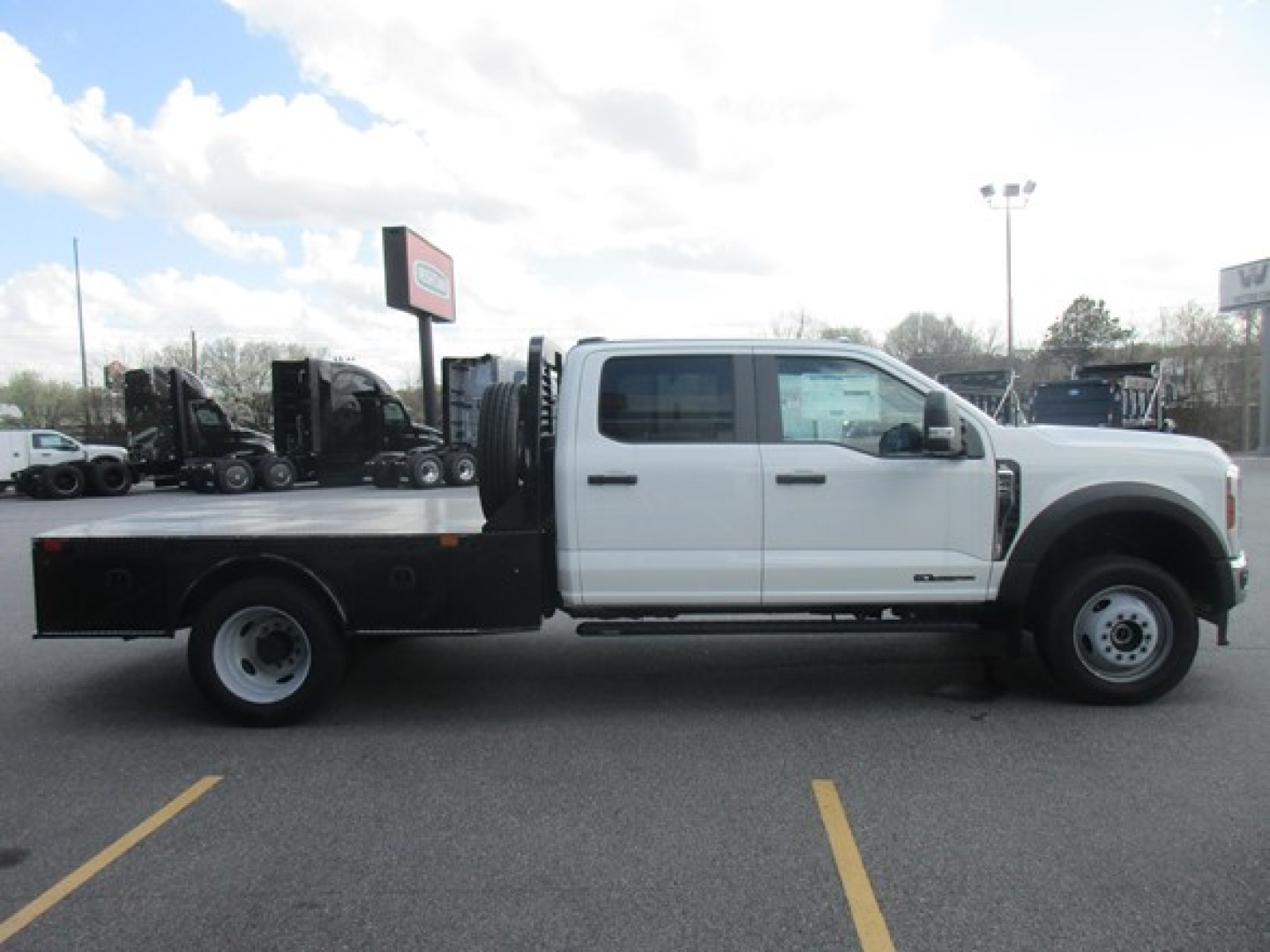 Ford F-450 flatbed truck side view showing white cab and black flatbed with dual rear wheels and storage compartments.
