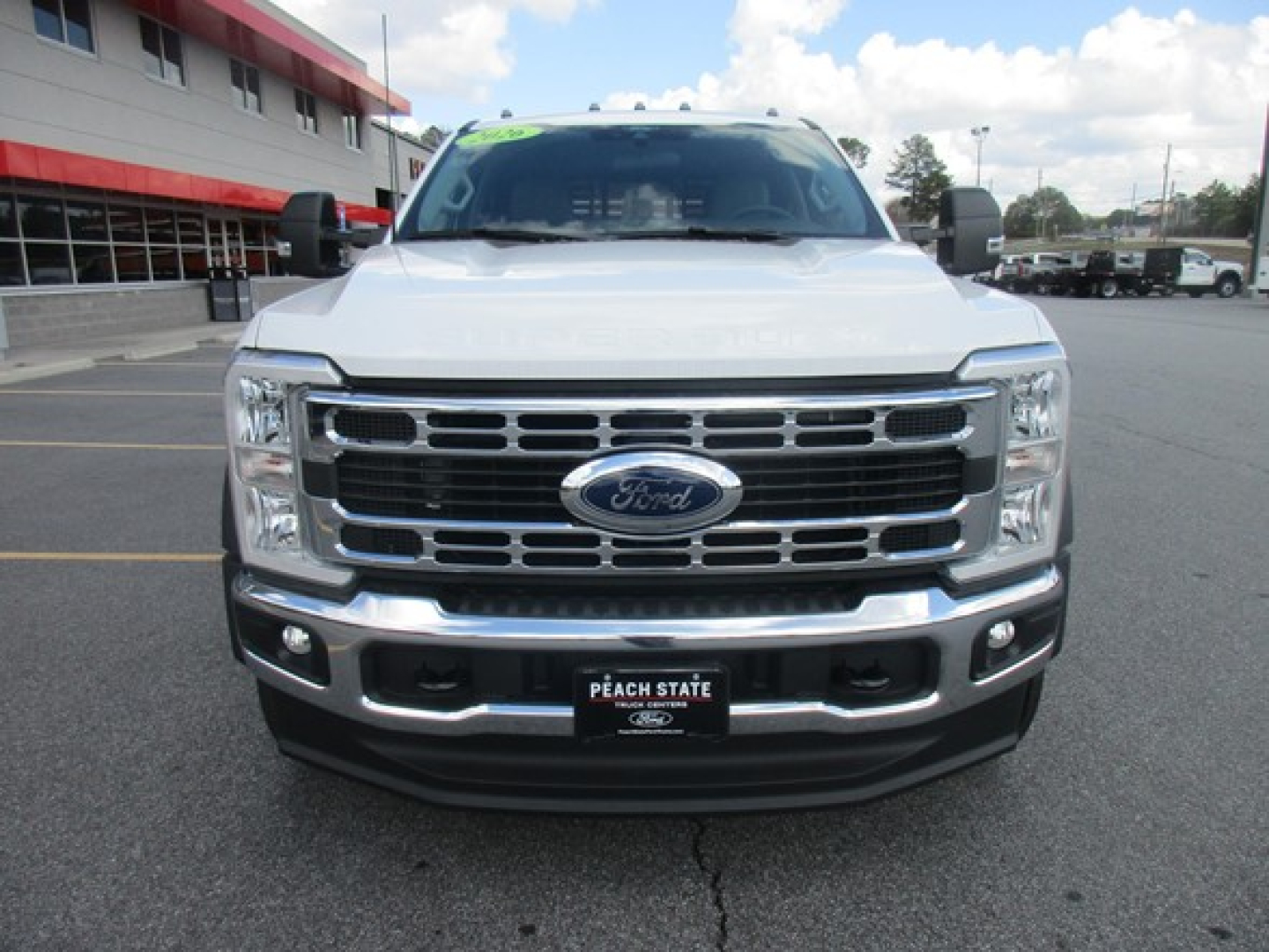 Front view of a white 2026 Ford F-450 flatbed truck showing chrome grille, Ford emblem, and bumper with Peach State license plate frame.