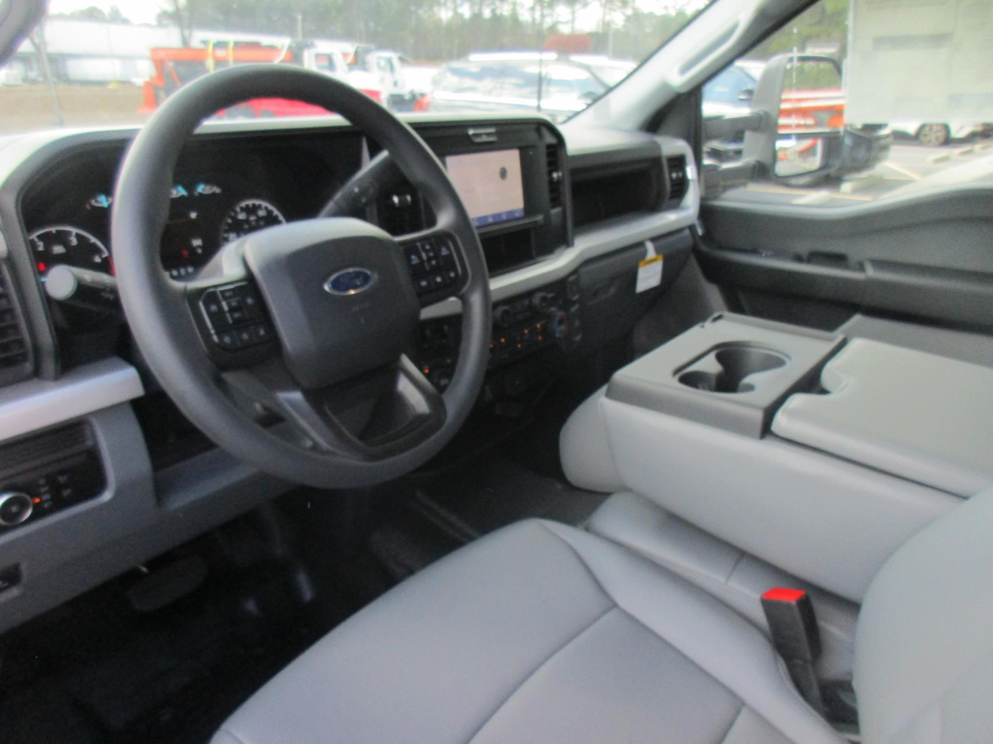 Ford F-450 interior view showing steering wheel, dashboard, center console, and light gray upholstery.
