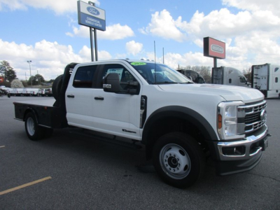 Ford F-450 flatbed truck in white with dual rear wheels and long flatbed, front grille, side mirrors, and black wheel arches visible.