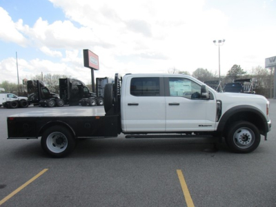 Ford F-450 flatbed truck side view showing white cab and black flatbed with dual rear wheels and storage compartments.