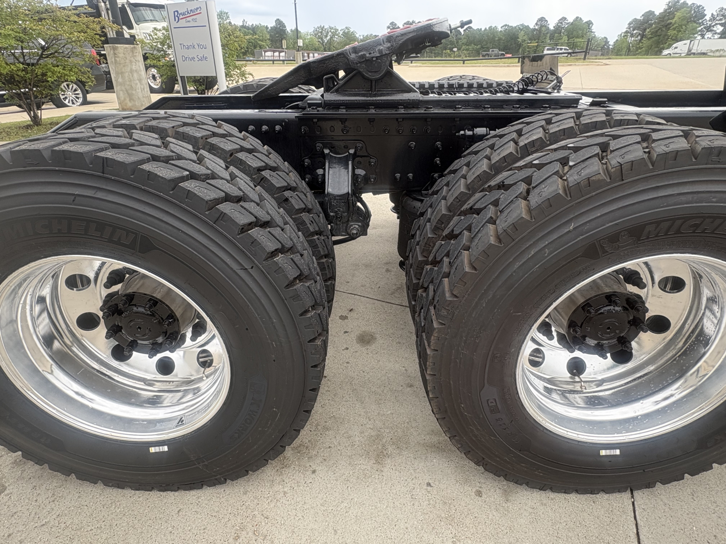 Dual rear axles on a Mack AN64T64 truck chassis showing two large all-terrain tires with chrome wheels and a visible center axle housing.