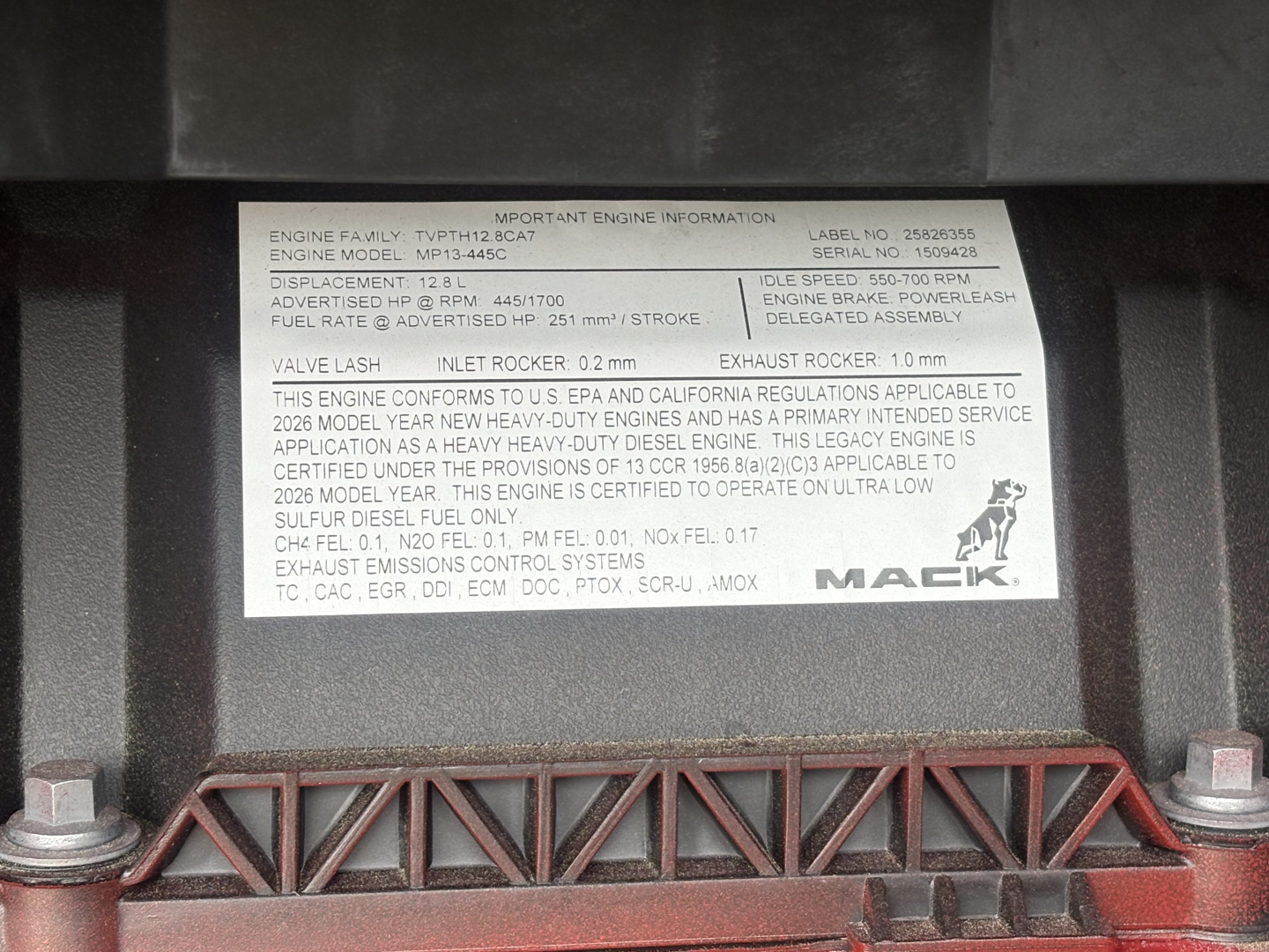 Mack engine information plate with engine family, model MPS-45C, discharge and RPM data, and VIN/serial details; visible label on truck engine area.