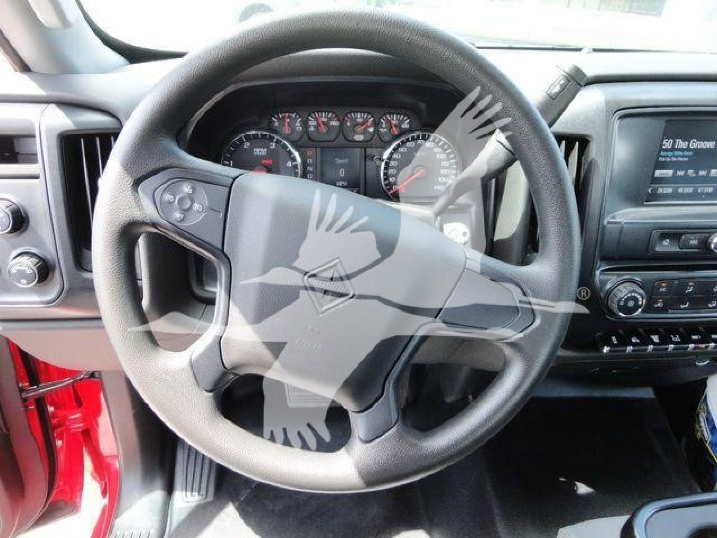 Truck cab interior focusing on steering wheel and dashboard. Steering wheel center badge and instrument cluster visible. Dashboard controls and infotainment screen to the right.