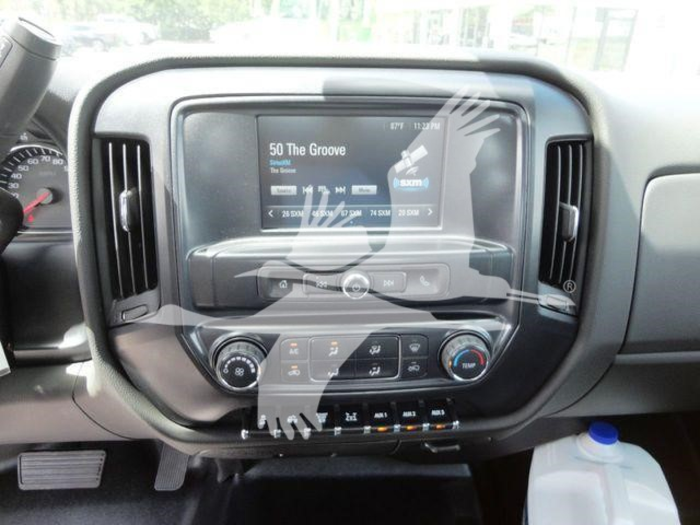Dashboard of a truck with a central touchscreen displaying media information and climate controls. Buttons and dials around the screen; some text on the screen is visible.