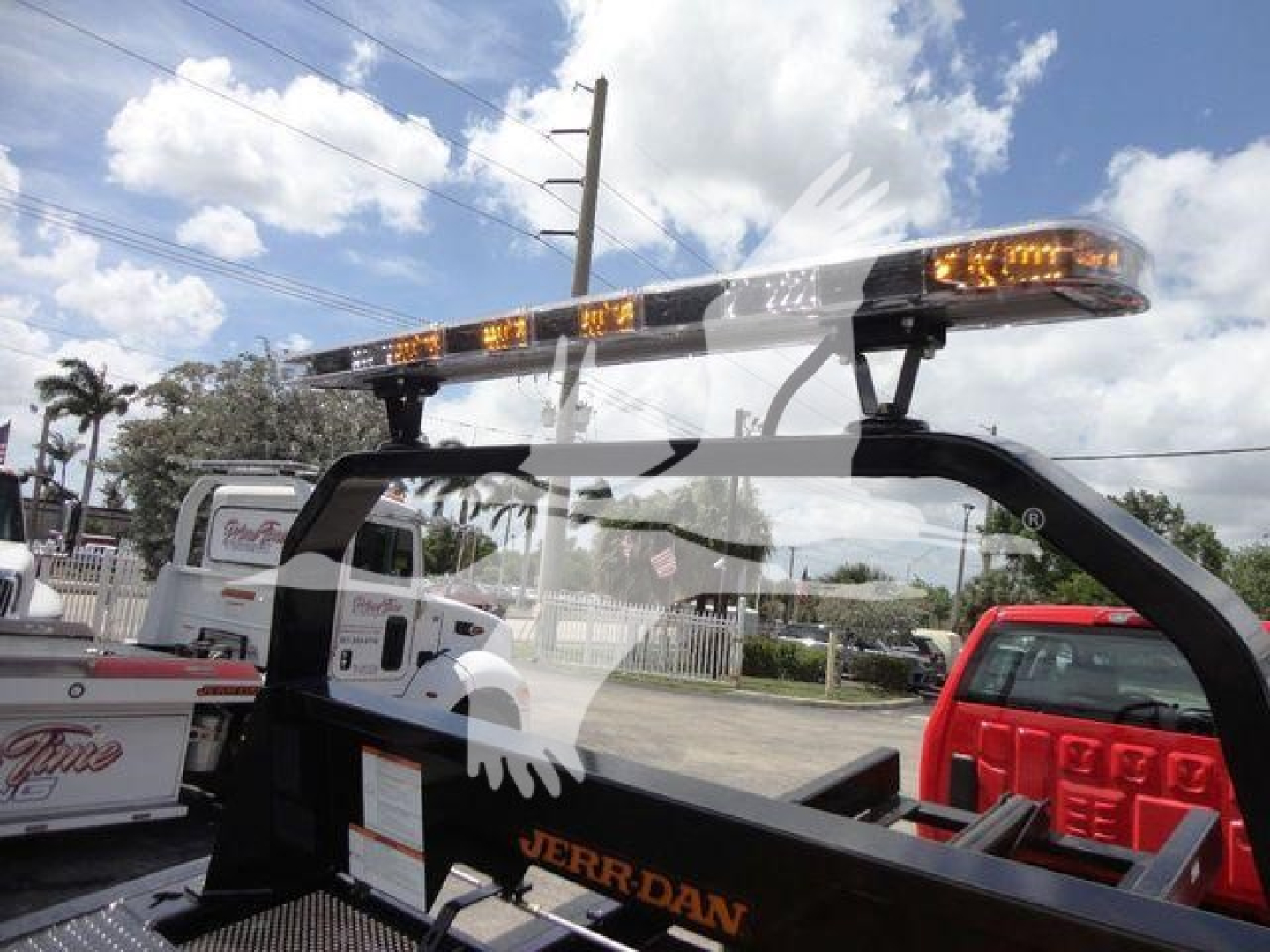 Lightbar-equipped International CV rollback truck cab with amber warning lights on top and Jerrycan branding visible on the side rail.