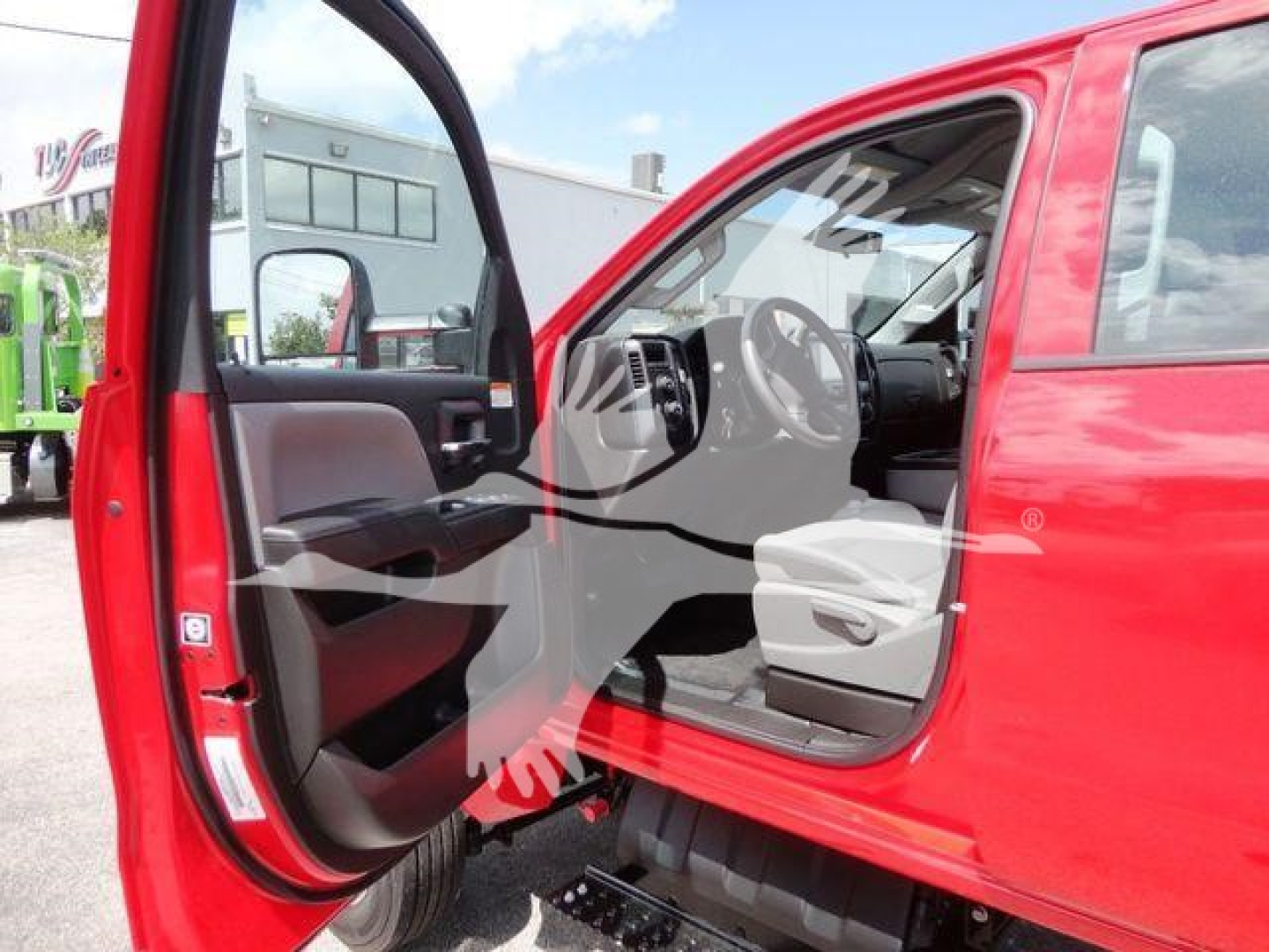 Truck cab interior with open driver door, red exterior, steering wheel and dashboard visible.