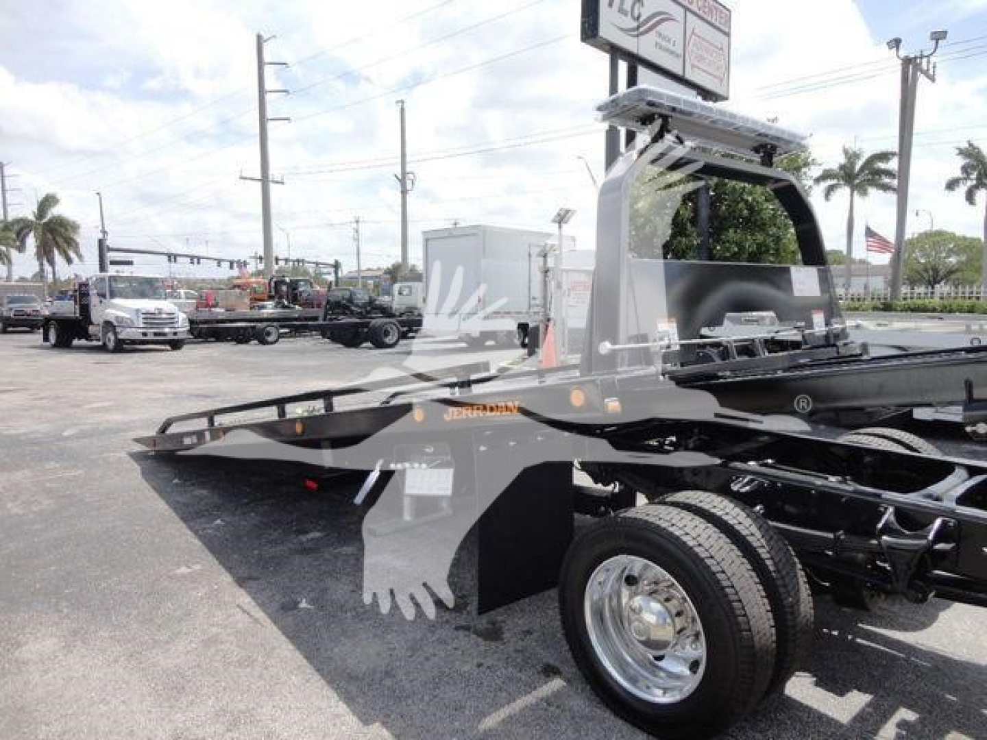 Truck rollback bed with dual rear wheels and metal hydraulic frame, side view showing flatbed and hitch area.