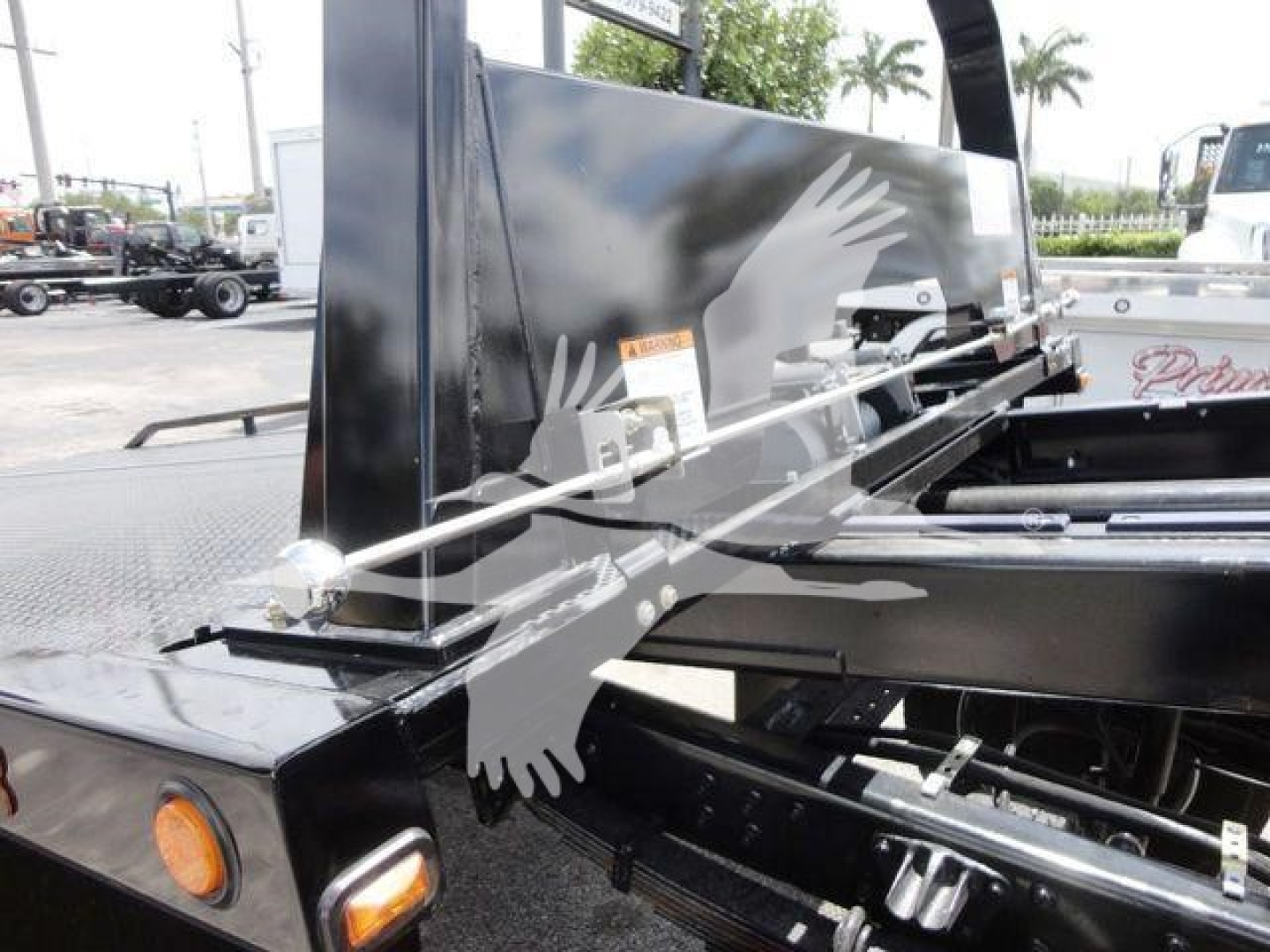Truck equipment with hydraulic rollback bed and flat steel components showing chrome bars and hinge mechanisms.