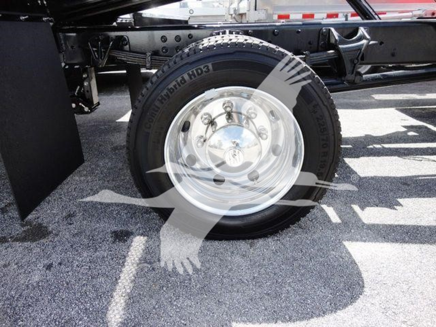 Truck wheel and tire assembly on a rollback truck showing a polished chrome hub with lug nuts and tire sidewall text.