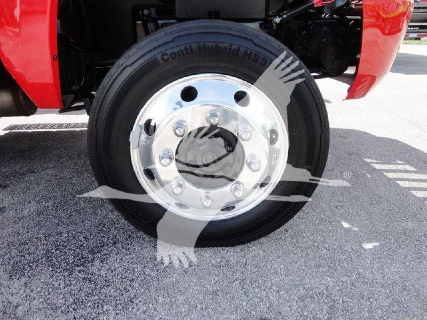 Truck wheel with Conti Hybrid HS3 tire showing chrome hub with lug nuts and wheel cover; vehicle red fender visible.