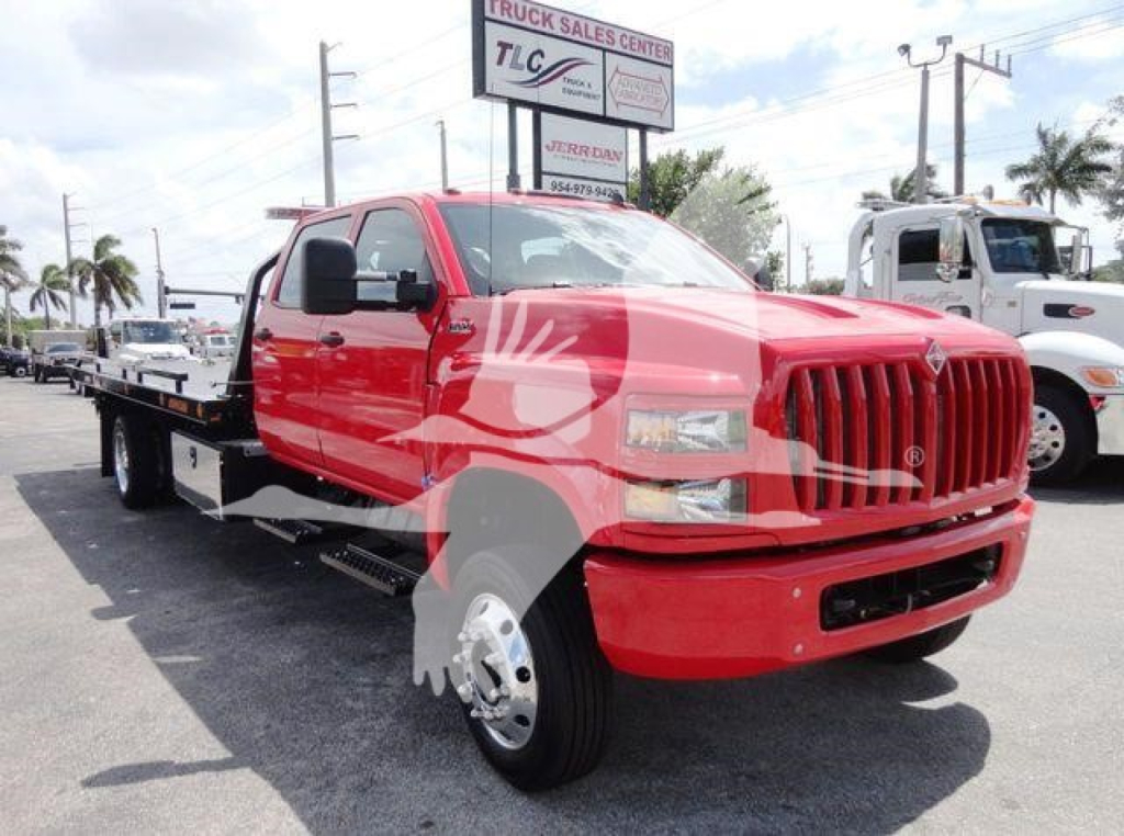 Truck bay showing a red 2023 International CV rollback flatbed, front grille and dual rear axles visible.