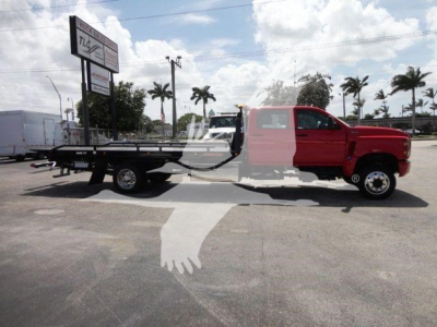 2023 International CV rollback truck with flatbed, red cab, long wheelbase, side view.