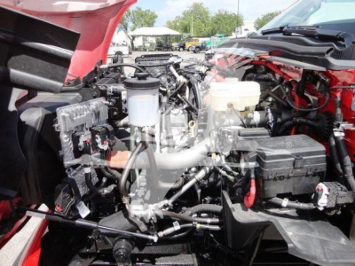 Truck engine bay with exposed components and wiring; visible reservoirs and hoses under open hood.
