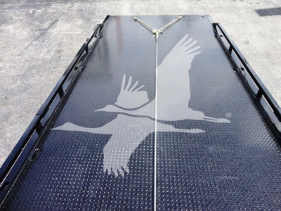 Truck flatbed with diamond plate deck and a white flying eagle decal; metal tracks along sides and a central tie-down rope.