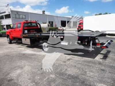 Red International CV heavy-duty rollback tow truck with a flatbed and black accents, parked outdoors near a service facility.