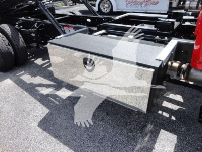 Truck chassis with a large rectangular toolbox mounted between rear wheels and frame.