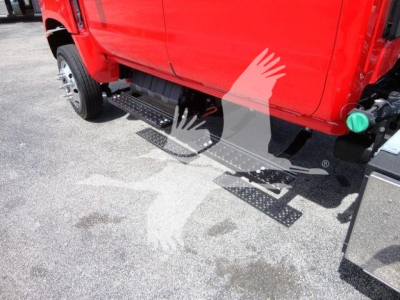 Truck side view showing metal side steps/rails beneath a red International CV cab.