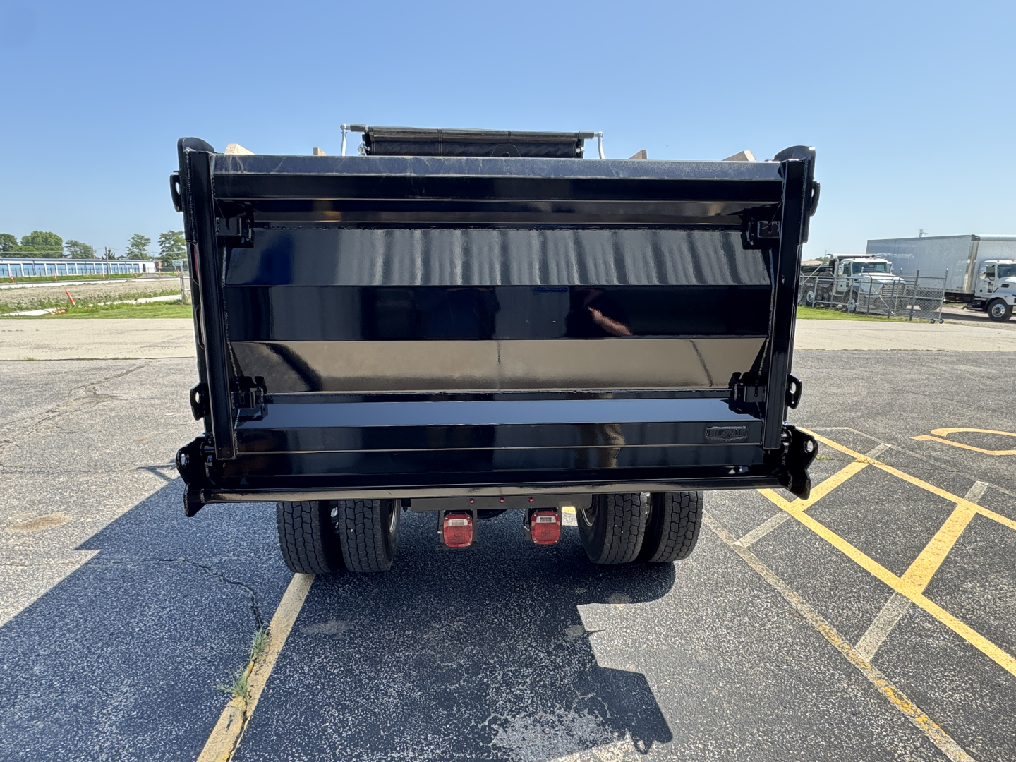 Dump truck bed of a 2025 Mack MD7 with black dumping box and dual rear wheels visible from rear view.