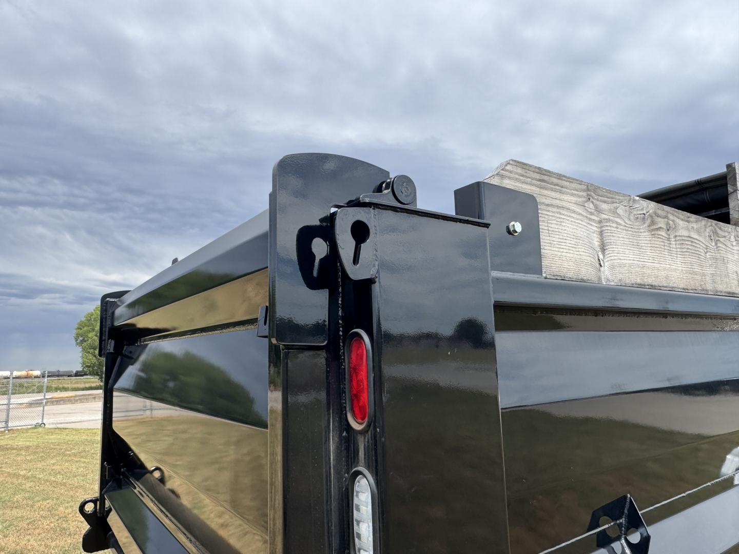 Dump truck bed of a 2025 Mack MD7 showing tailgate hinges and reflective black exterior.