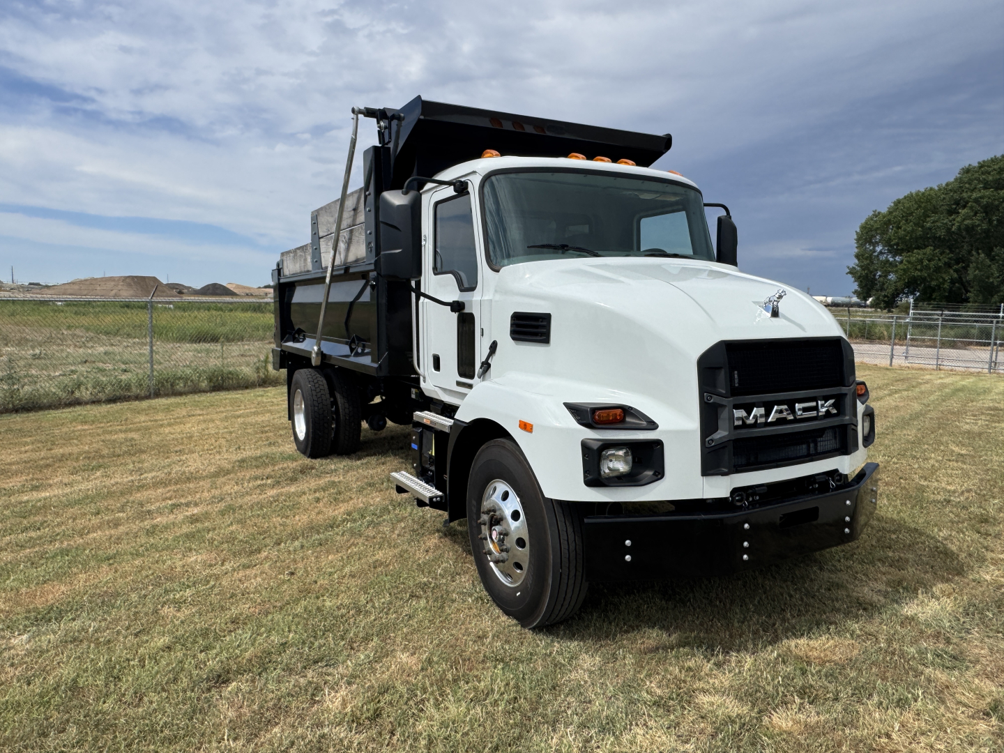 White 2025 Mack MD7 dump truck with black grille and dump bed, front view angled, VIN 1M2MDBAB6SS076360, stock 66557.