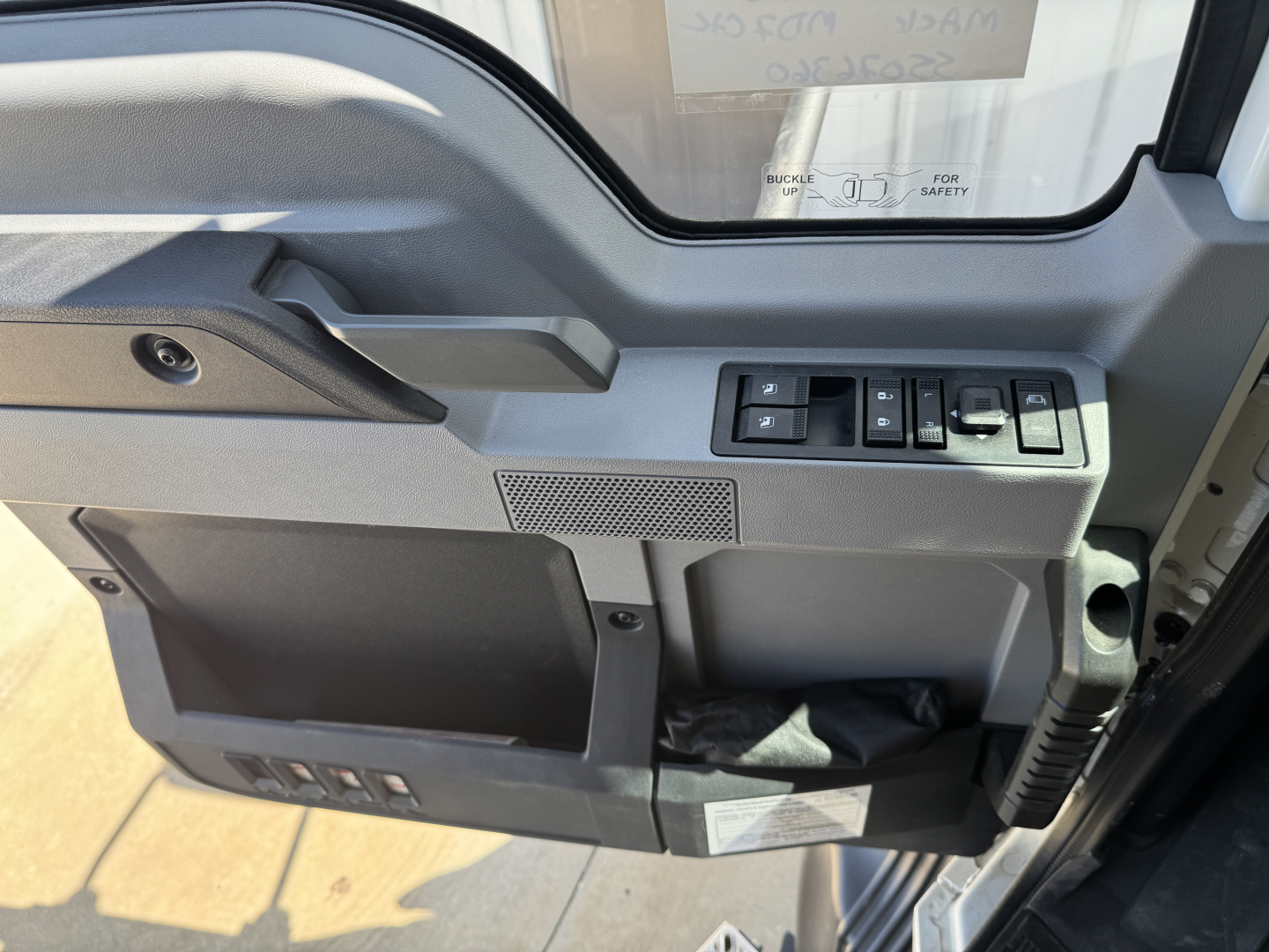 Mack MD7 cabin interior side door panel showing window controls, storage pocket, and switches.