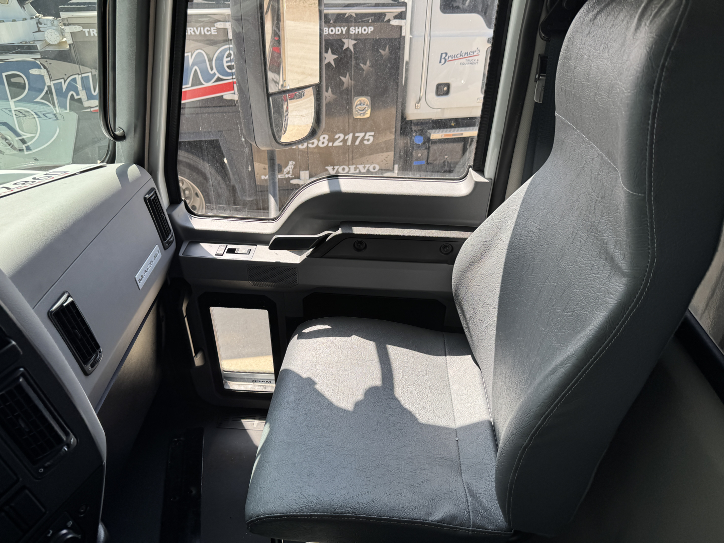 Truck cab interior showing driver's seat and dashboard in a Mack MD7 truck.