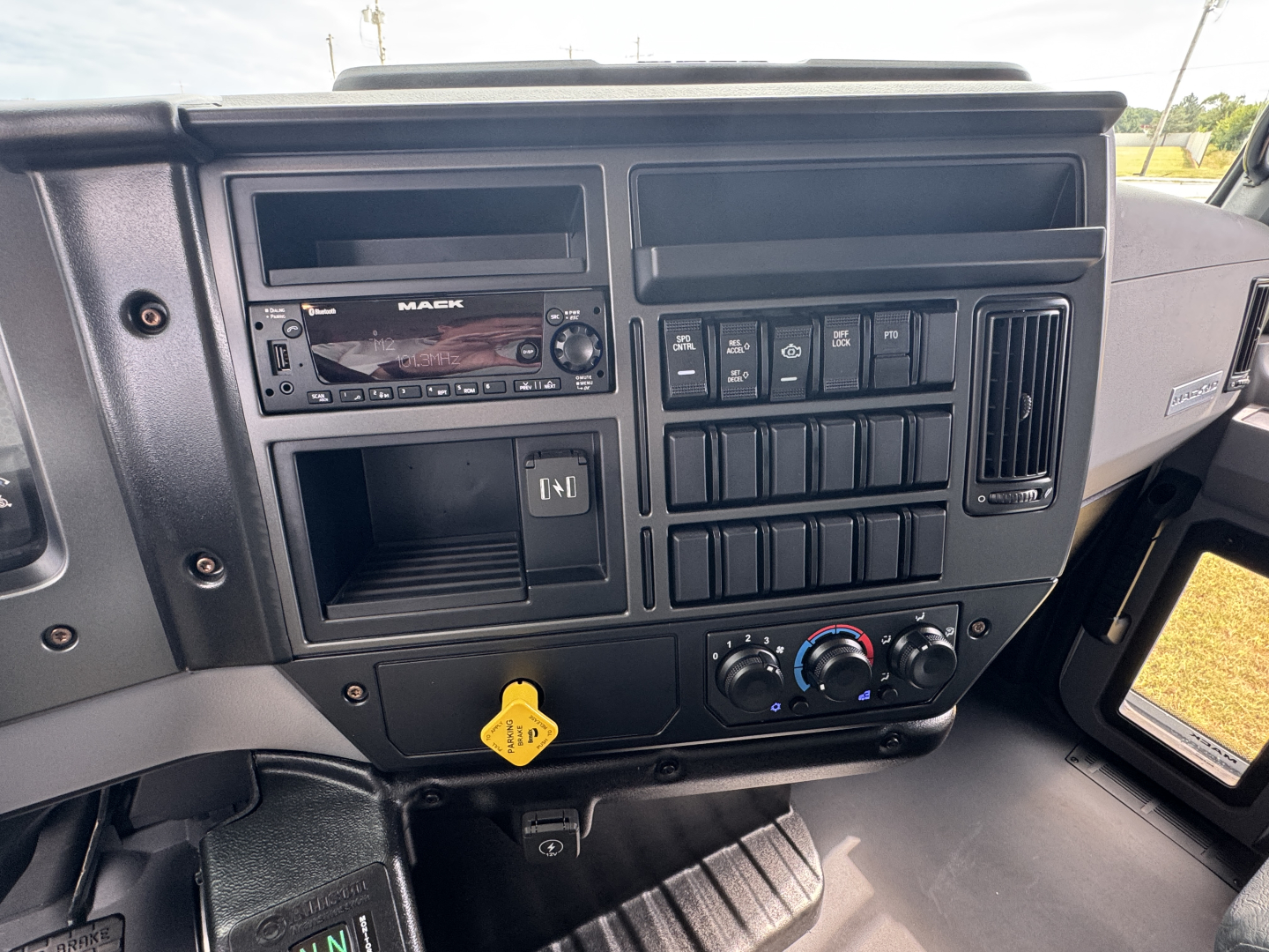 Cab dashboard of a 2025 Mack MD7 dump truck showing radio unit, control switches, and climate controls.