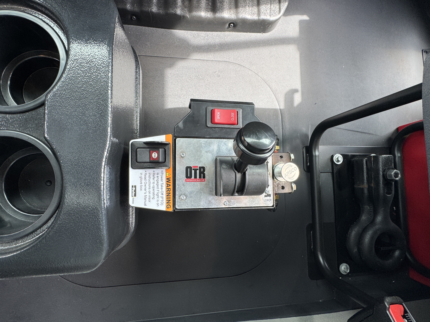 Dashboard area showing a switch panel with red on/off toggle and a label reading DTR or OTR, plus a small yellow warning label. Cup holders visible on left.