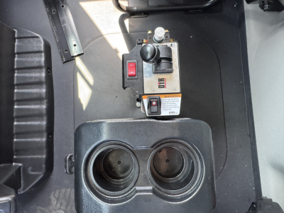 Two cup holders and a control panel in a Mack MD7 dump truck cab area with switches and warning label visible.