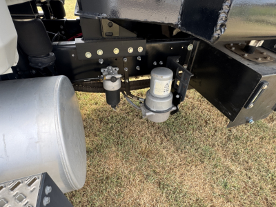 Mack MD7 chassis showing fuel/water separator filter and hydraulic lines under truck frame.