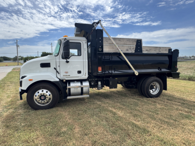 Dump truck side view showing white cab and black dump bed with hydraulic tarp bar.