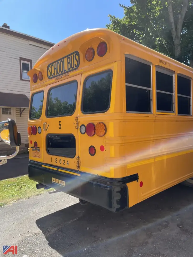 Yellow school bus rear view showing taillights, bumper, and windowed rear doors with 'SCHOOL BUS' sign above; vehicle identification numbers and reflective decals visible.