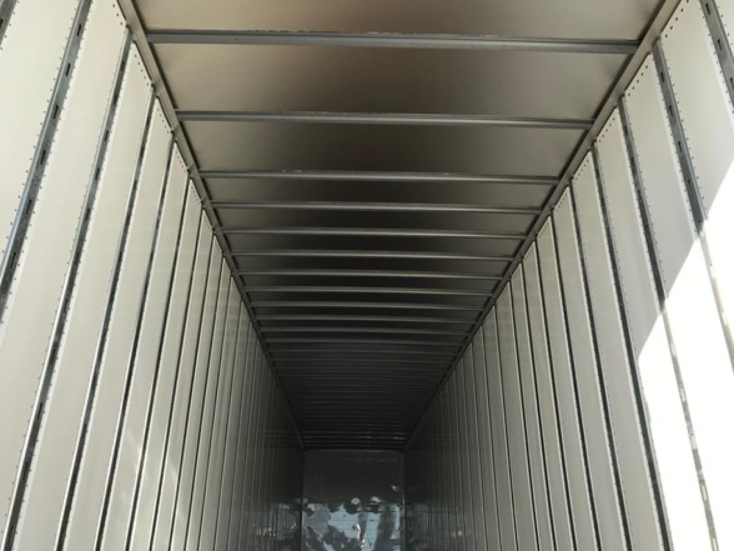 Trailer interior showing a long, empty box with metal sidewalls and a ribbed ceiling, cargo area viewed from rear opening.
