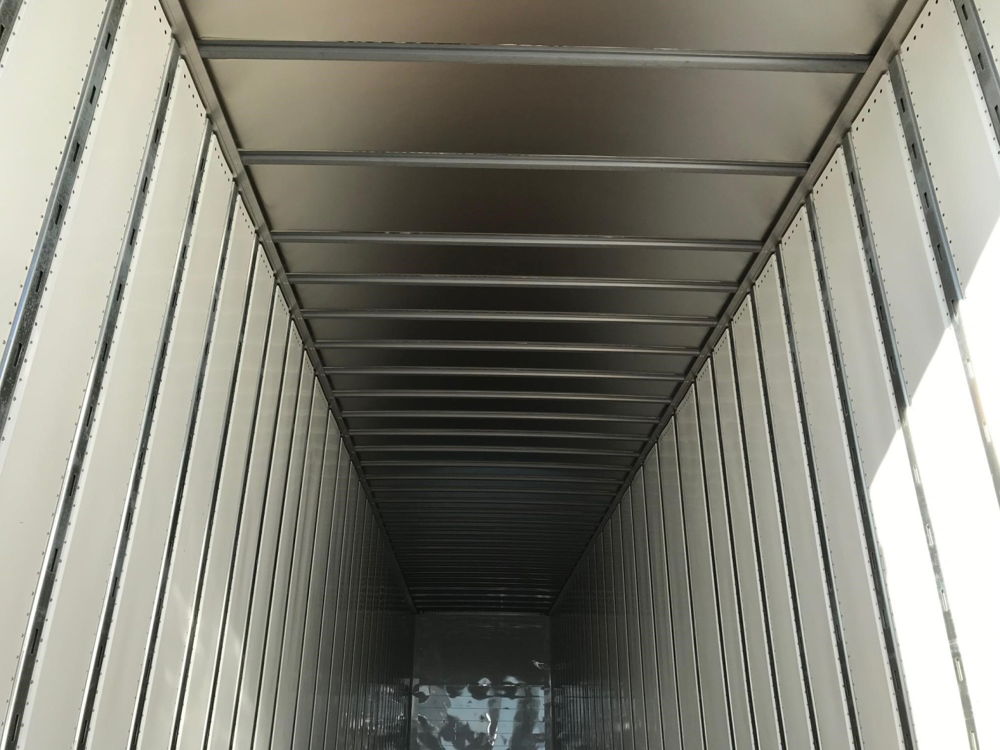 Trailer box interior showing metal sidewalls and ceiling with evenly spaced horizontal support beams.