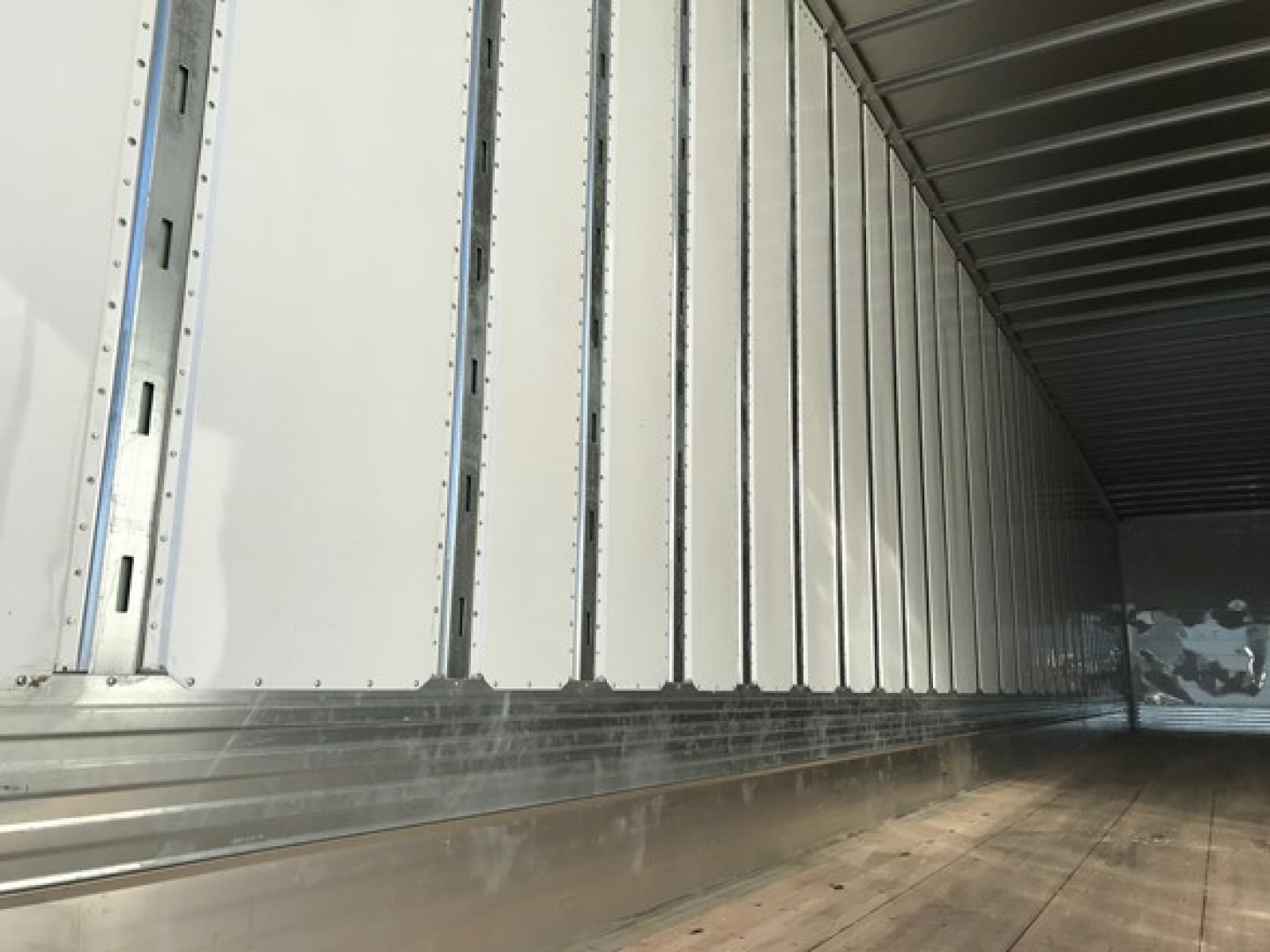 Trailer interior side walls with ribbed aluminum panels and wooden floor showing utility trailer cargo area.