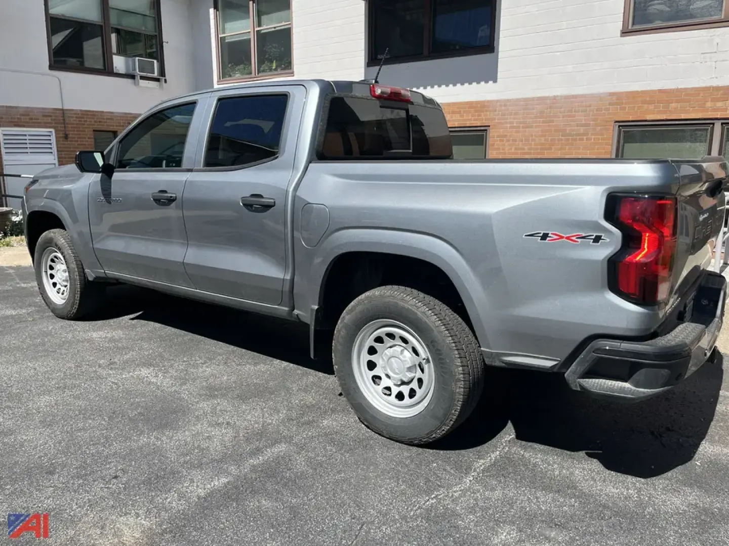 Chevrolet Colorado pickup truck in silver extended cab 4x4 with tailgate 3/4 view showing bed, rear taillight, and 2 rear doors.