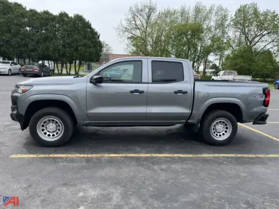 Side view of a gray 2024 Chevrolet Colorado extended cab pickup truck in a parking lot.