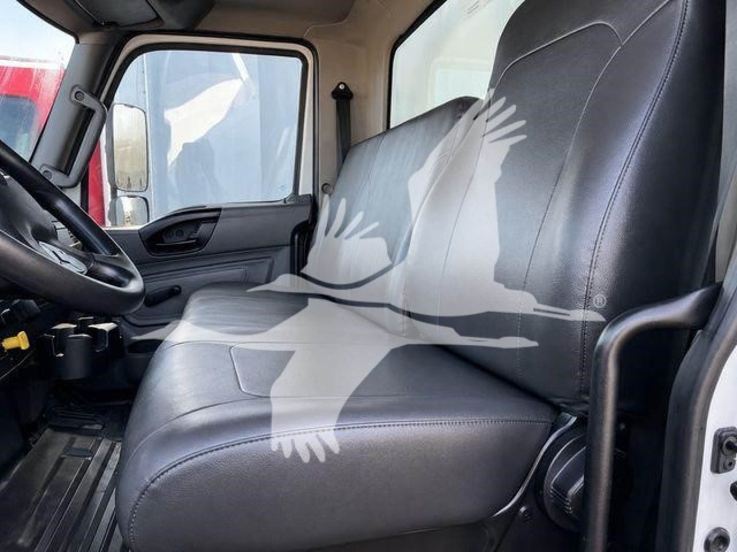 Interior of a 2021 International MV truck cab showing black vinyl driver seat, steering wheel, and dashboard with window.