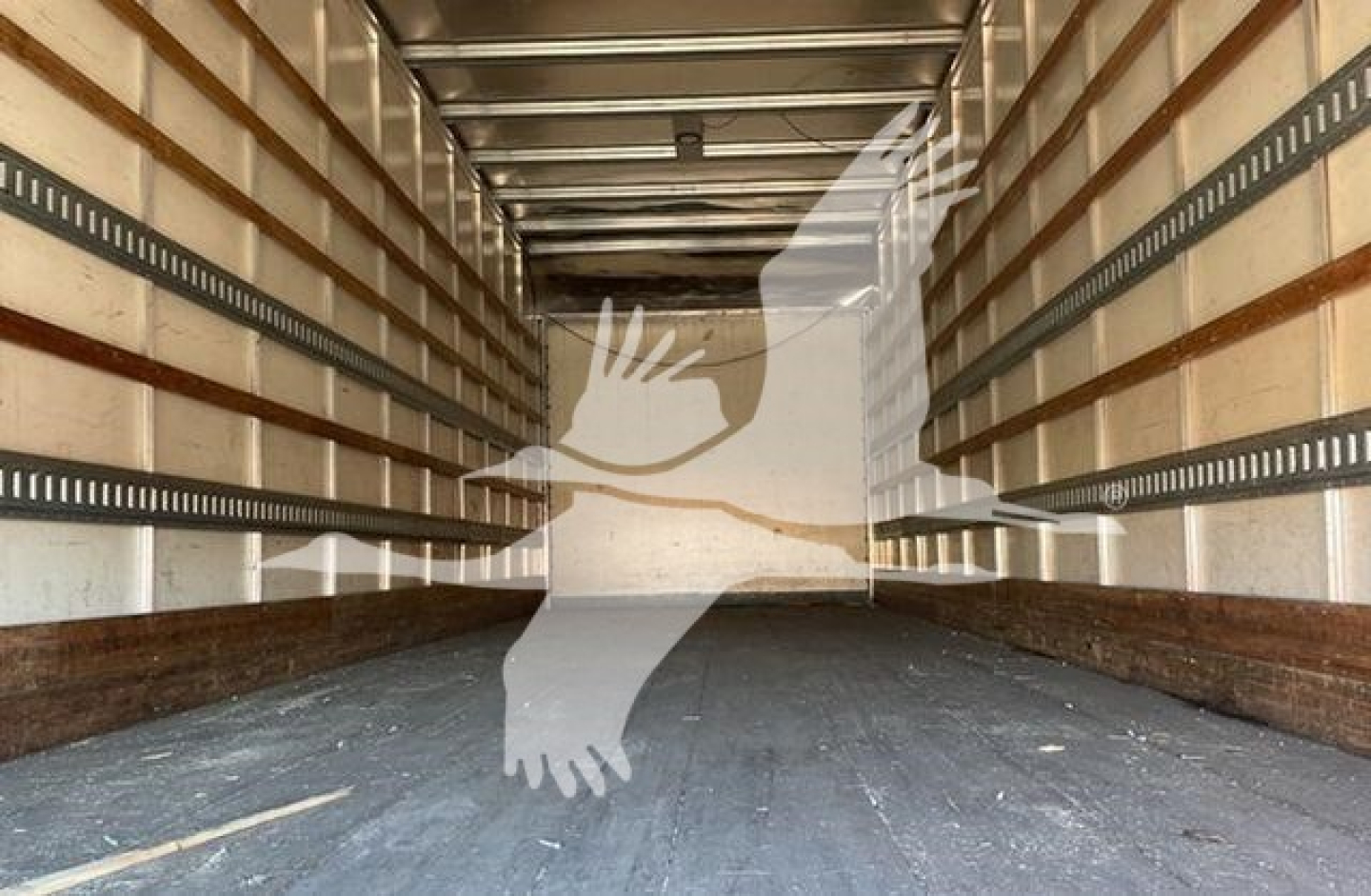 Interior of empty cargo box trailer with wooden side rails and metal tracks, seen from rear opening.